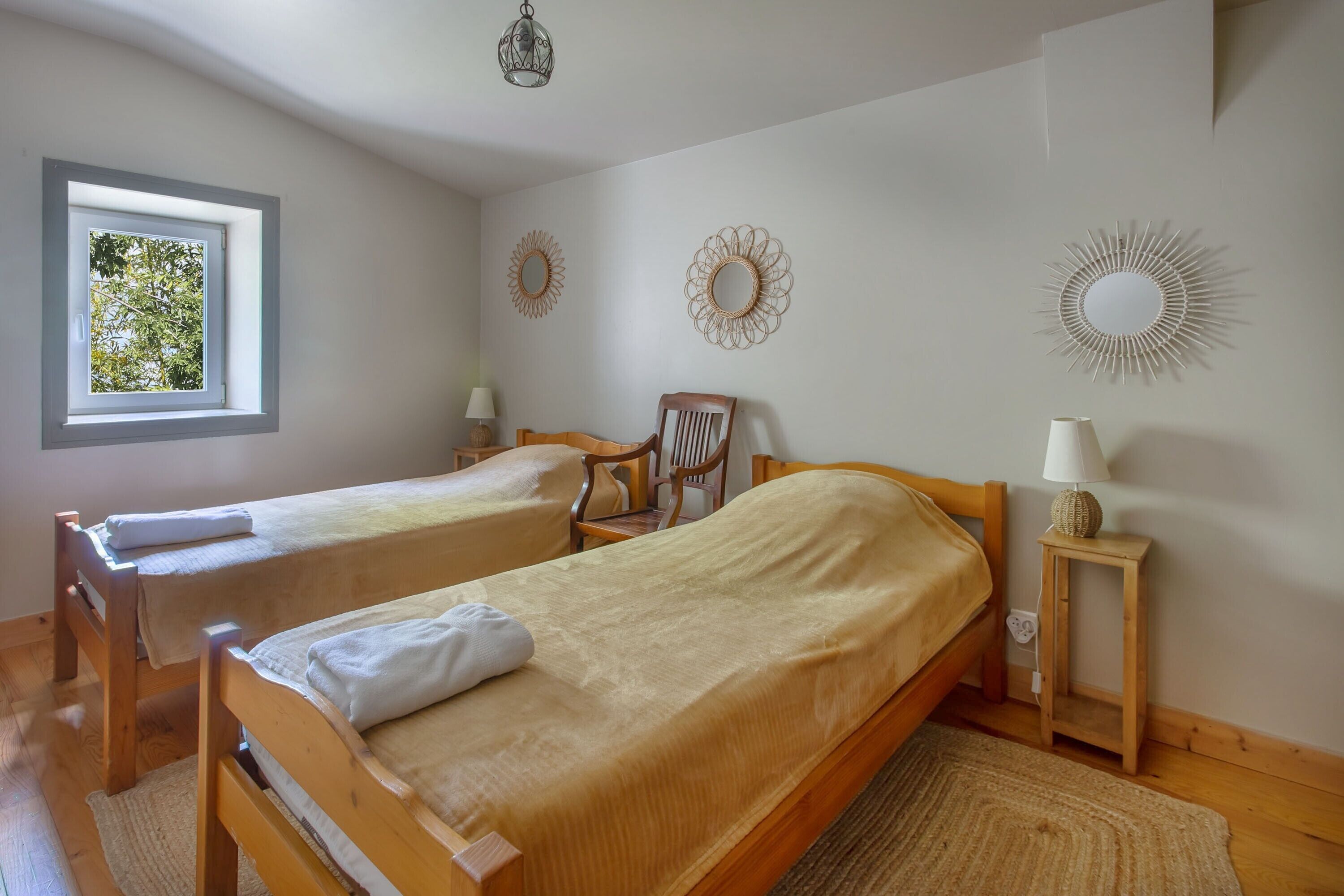 Ein Schlafzimmer mit zwei Holzbetten, einem Fenster und Wanddekoration.