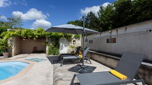 A poolside area with lounge chairs, a table, and an umbrella. - Holiday Home 'Aux Agapanthes', Shared Pool, Private Terrace, Landscaped Park, Free Wi-Fi (Aumagne)