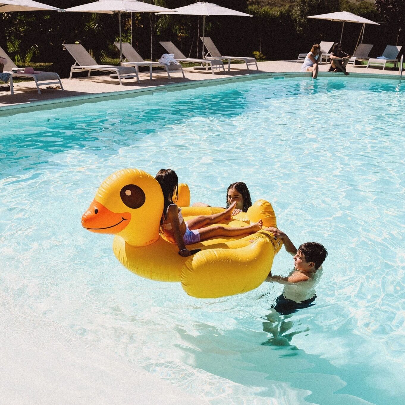 A swimming pool with lounge chairs and umbrellas.