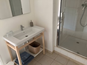 Une salle de bain avec un lavabo blanc, un miroir et une douche.