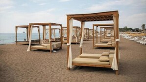 Een strand met houten ligbedden en parasols voor gasten.