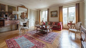 A spacious living room with a fireplace, a sofa, a coffee table, and a large mirror. - Parisian Muse, by Veeve (Paris)