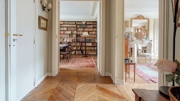 A hallway with a herringbone floor leading to a room with a bookshelf, a mirror, and a statue. - Parisian Muse, by Veeve (Paris)