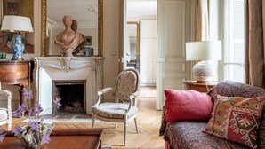 A room with a fireplace, a large mirror, a chair, a sofa, and a table with a vase of flowers. - Parisian Muse, by Veeve (Paris)
