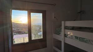 A room with a window overlooking a landscape, a bunk bed, and a wall-mounted electrical outlet. - 7 Calcosas (Valverde)