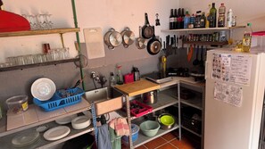 A kitchen with shelves holding wine bottles, cooking utensils, and a refrigerator with a menu.