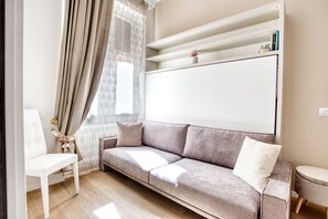 A modern living room with a sofa, a white chair, a small table, and a whiteboard on the wall. - Easylife - Milano - Bertacchi 1S - Milano  (Milano)