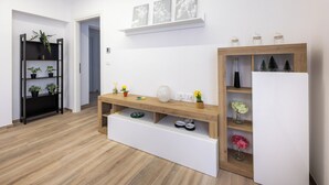 A modern living room with a wooden floor, a white sofa, a wooden coffee table, a black bookshelf, and a white cabinet with glass jars. - Nadia Flat - 10 minutes from the beach (Montesilvano)