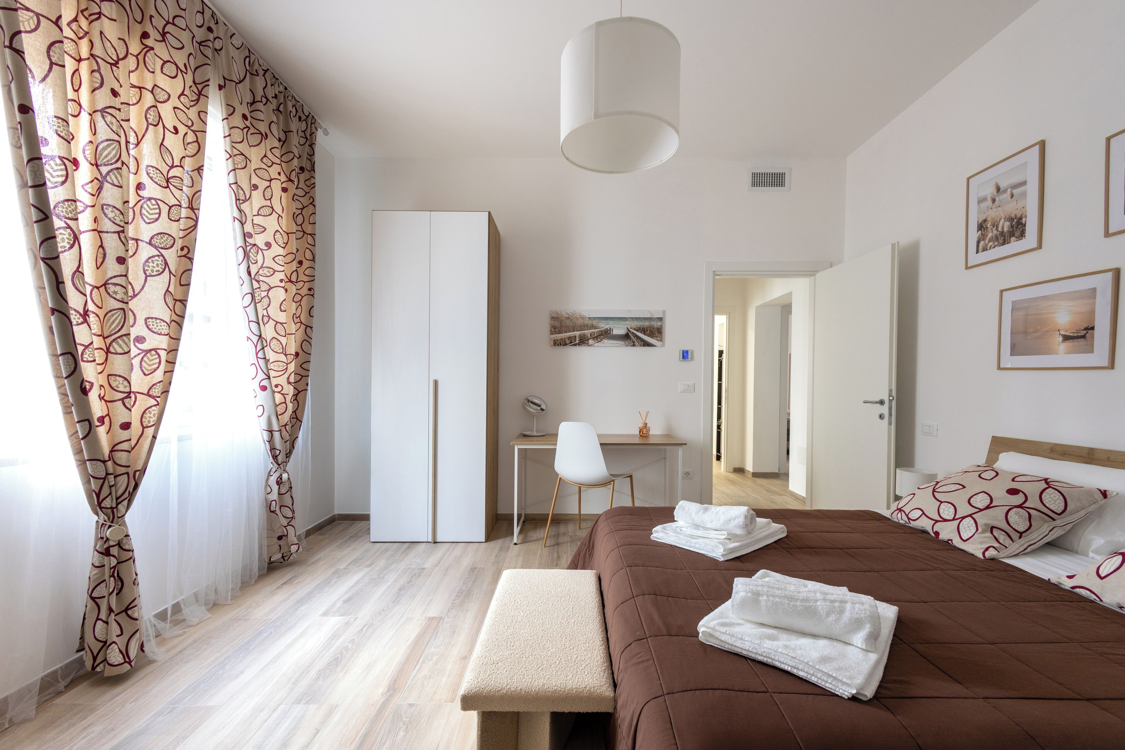 Une chambre à coucher comprenant un lit, un bureau, une chaise, une armoire et un banc.