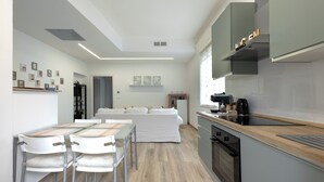 A modern kitchen with a built-in oven, a dining area with a table and chairs, and a living area with a sofa. - Nadia Flat - 10 minutes from the beach (Montesilvano)