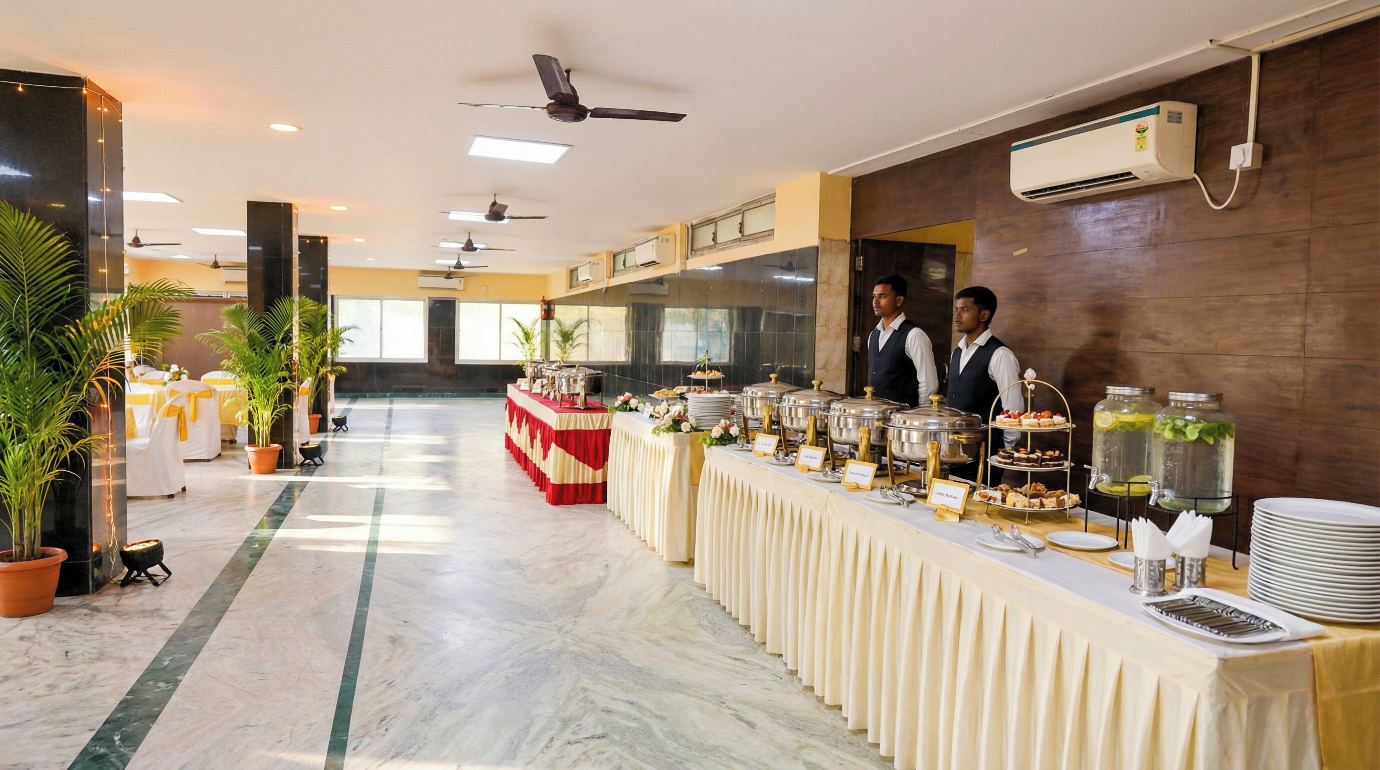 A buffet setup with multiple food stations, ceiling fans, and air conditioning units.