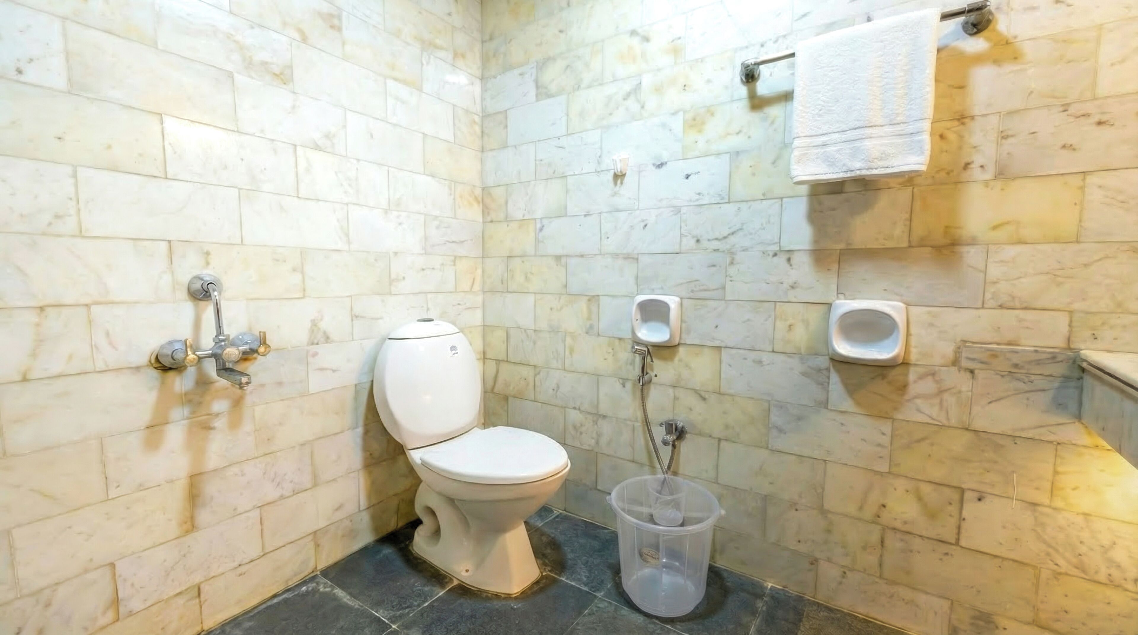A bathroom with a toilet, a hand basin, and a trash bin.