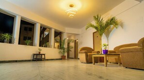 A spacious lobby with a marble floor, large windows, and a modern chandelier.