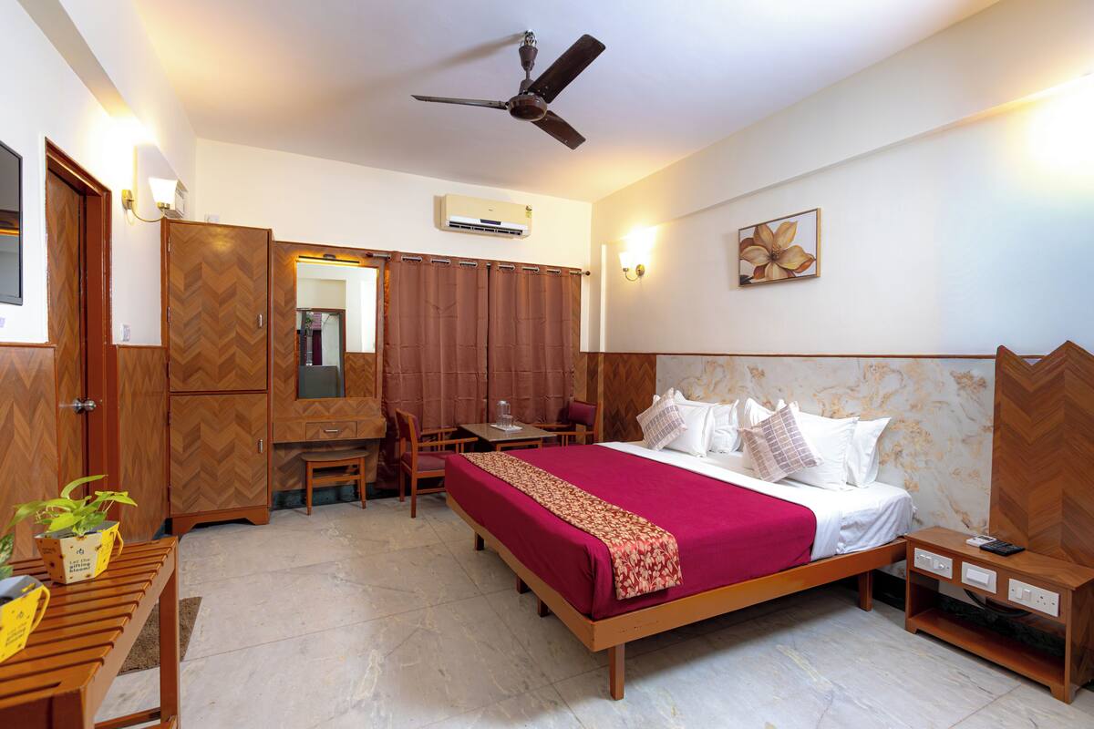 A hotel room with a bed, desk, chair, and a ceiling fan.