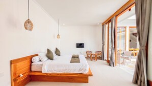 Ein Schlafzimmer mit einem hölzernen Bett, einem Fernseher, einem Balkon mit Stühlen und einem großen Fenster.