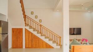 Ein modernes Interieur mit einer Holztreppe, einem Flachbildfernseher und einem Bett mit Kissen.