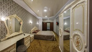 A bedroom with a bed, a dresser, a mirror, and a door leading to another room.