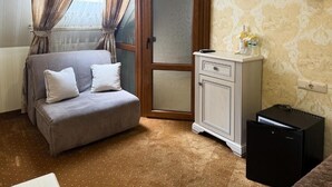 A room with a bed, a cabinet, a radiator, and a window with curtains.