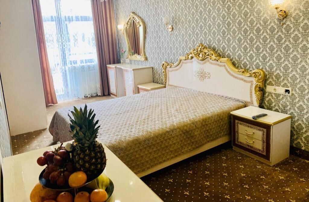 A hotel room with a bed, bedside table, and a fruit bowl on the table.