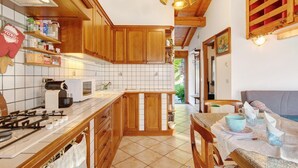 Una cocina con armarios de madera, estufa a gas, microondas y comedor con mesa y sillas.
