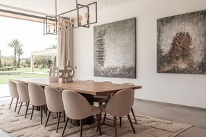 Ein moderner Essbereich mit einem Holztisch, sechs Stühlen und abstrakter Kunst an der Wand.