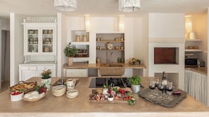 Una cocina con isla central, armarios blancos e iluminación colgante.