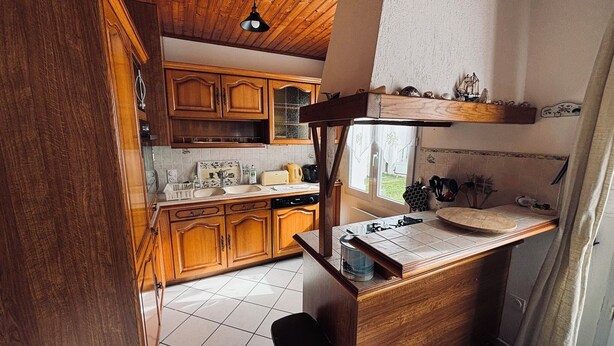 Eine Küche mit Holzschränken, einem Spülbecken und einem Fenster.