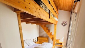 Ein kleines Zimmer mit Etagenbett, einer Holztreppe und einem kleinen Nachttisch.