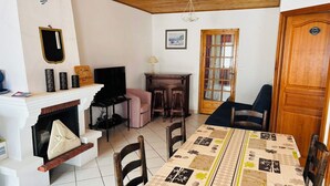 Ein Wohnzimmer mit Kamin, Fernseher und einem Esstisch mit gemustertem Tischläufer.