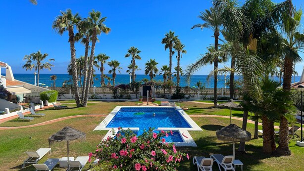 A pool with lounge chairs, palm trees, and a view of the ocean. - La Caleta 'Mediterranean beachfront house' (Caleta de Vélez)