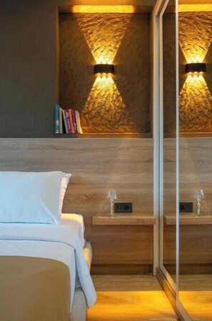 Ein modernes Hotelzimmer mit einem Holz-Kopfteil, Nachttischen mit Gläsern und einer Wandgestaltung mit Struktur.