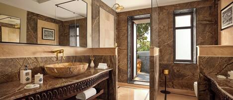 Un baño moderno con un espejo grande, un lavabo de madera, paredes de mármol y vistas al exterior.