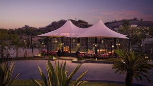 A glass-roofed pavilion with a white canopy, surrounded by landscaped gardens and palm trees. - Storii By ITC Hotels Jawai (Bali)