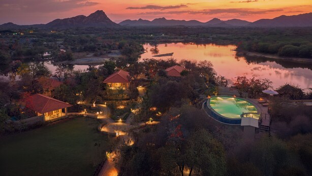 A resort with a swimming pool, multiple buildings, and a lake. - Storii By ITC Hotels Jawai (Bali)