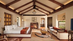 A spacious room with a large bed, a seating area, a dining table, and a view of the outdoors. - Storii By ITC Hotels Jawai (Bali)