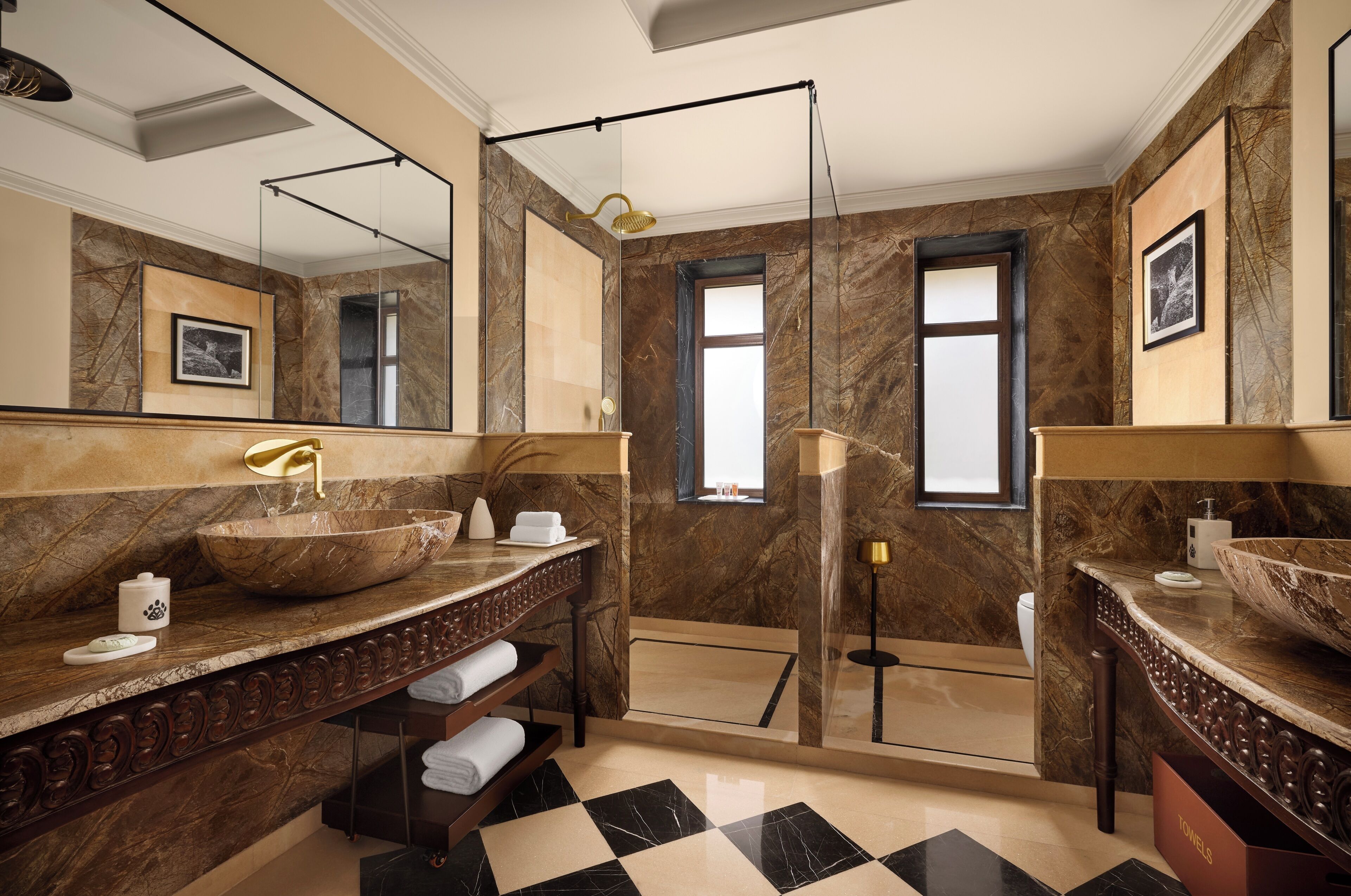 A bathroom with marble walls, two sinks, a large mirror, and a window.
