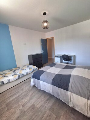 A bedroom with a bed, a desk, a chair, a wardrobe, and a hanging light fixture. - Country getaway (Charavines)