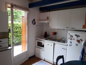 Eine kleine Küche mit weißen Schränken, einer Spüle, einem Herd und einem Kühlschrank.