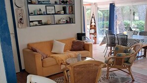 A living room with a sofa, wicker chairs, a coffee table, and a bookshelf.