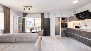 A modern apartment with a living area, kitchen, dining space, and a balcony with a city view. - AURA Superior Apartment (La Pineda)