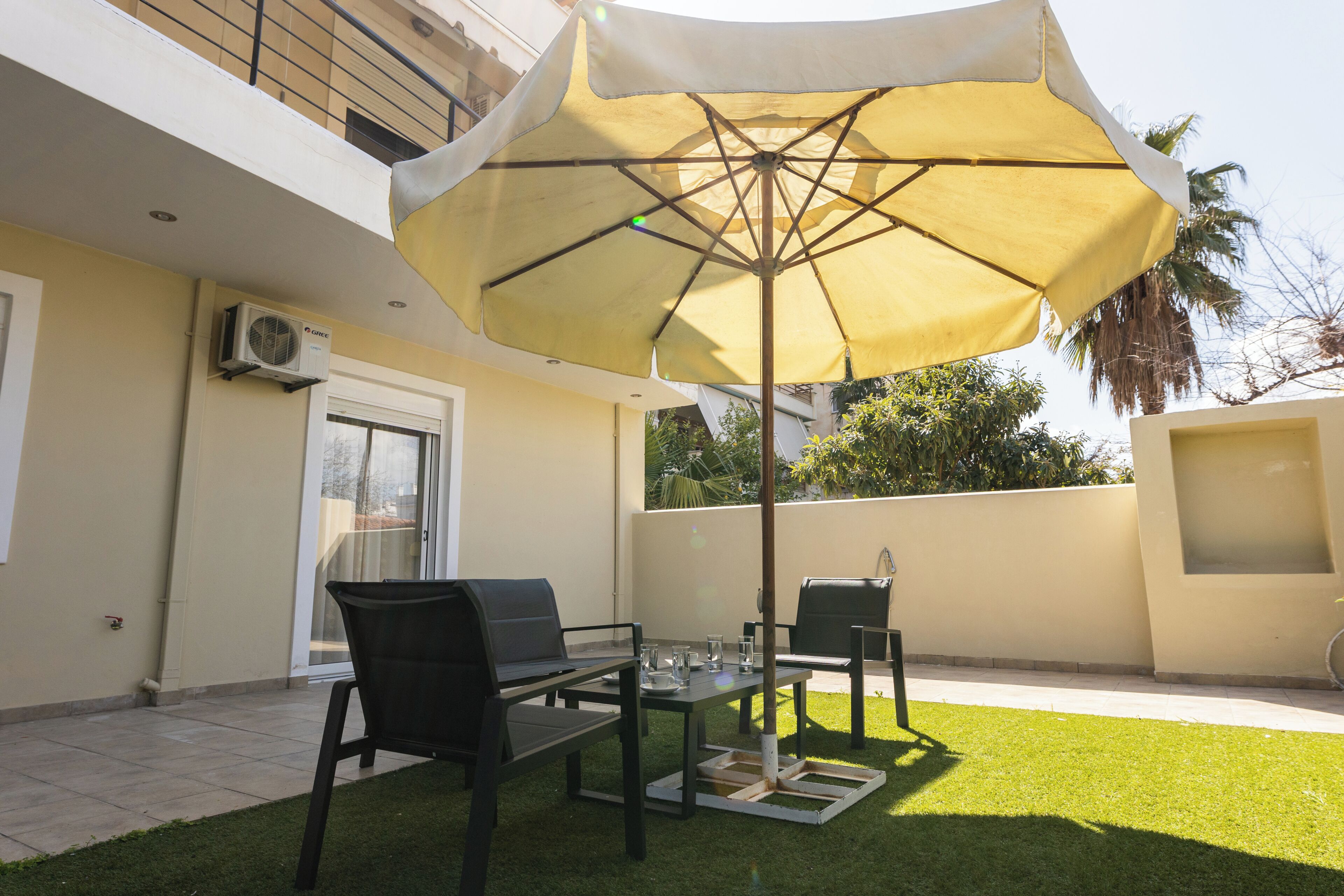 En udendørs terrasse med et bord, stole og en stor parasol.