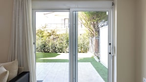 A room with a sliding glass door leading to a patio with a lawn and a fence.