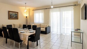 A dining area with a table set for four, surrounded by chairs, a sofa, and a glass table.