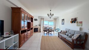 Una sala de estar con sofá, armarios de madera, televisor y chimenea.