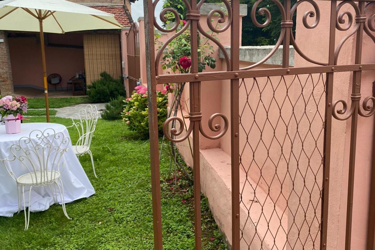 A patio with a table and chairs, a decorative fence, and a garden with flowers.