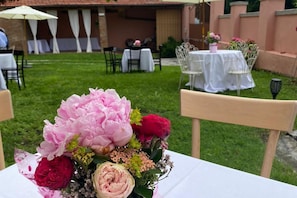 Une table agrémentée d’un centre de table floral, un espace de restauration en plein air avec des tables recouvertes de nappes blanches et des chaises.