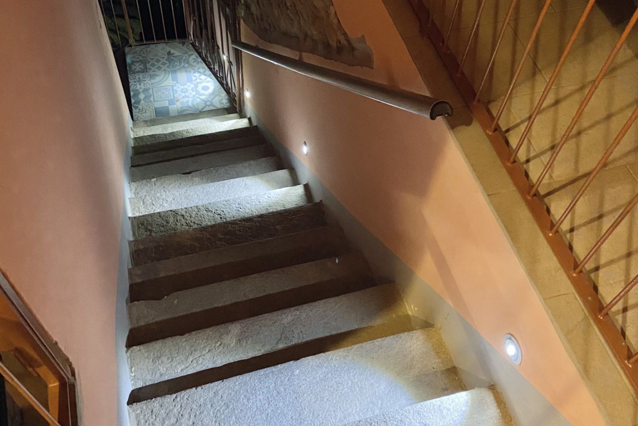 Un escalier avec une rampe, un sol à motifs et un mur à la surface texturée.