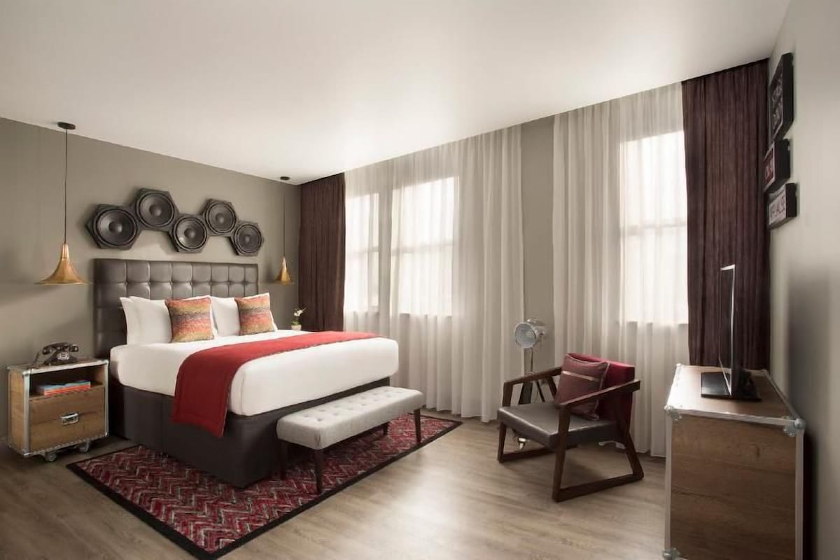A modern bedroom with a large bed, bedside tables, a desk, and a chair.