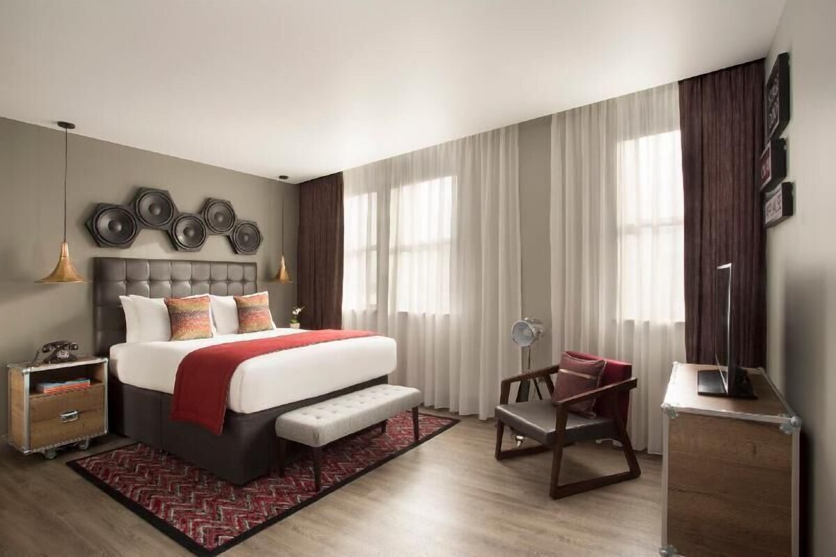 A modern bedroom with a large bed, bedside tables, a desk, and a chair.