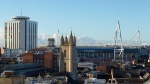 A cityscape with a prominent tower, a church with a spire, and a bridge with cables. - Hotel Indigo Cardiff (Cardiff)
